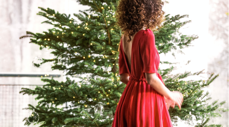 woman in red dress facing a Christmas tree