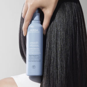 smooth infusion perfect blow dry spray held next to woman's head